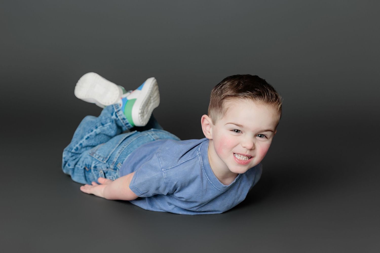 Child in denim lying on dark background in various playful poses creating a dynamic photo sequence.