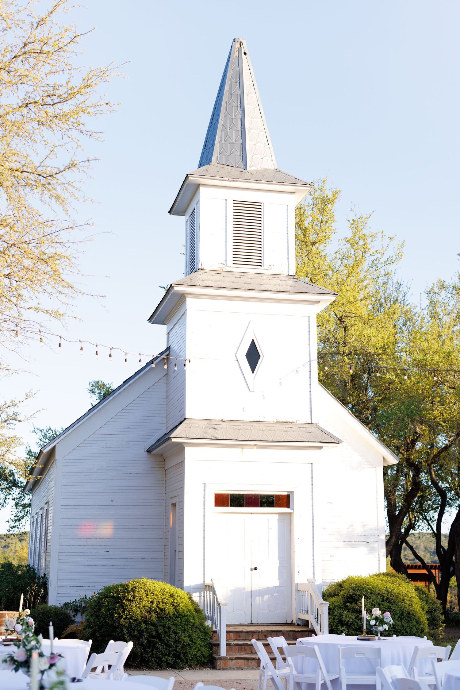 A series of four similar views of a white country church with a steeple against a blue sky and trees in the background.