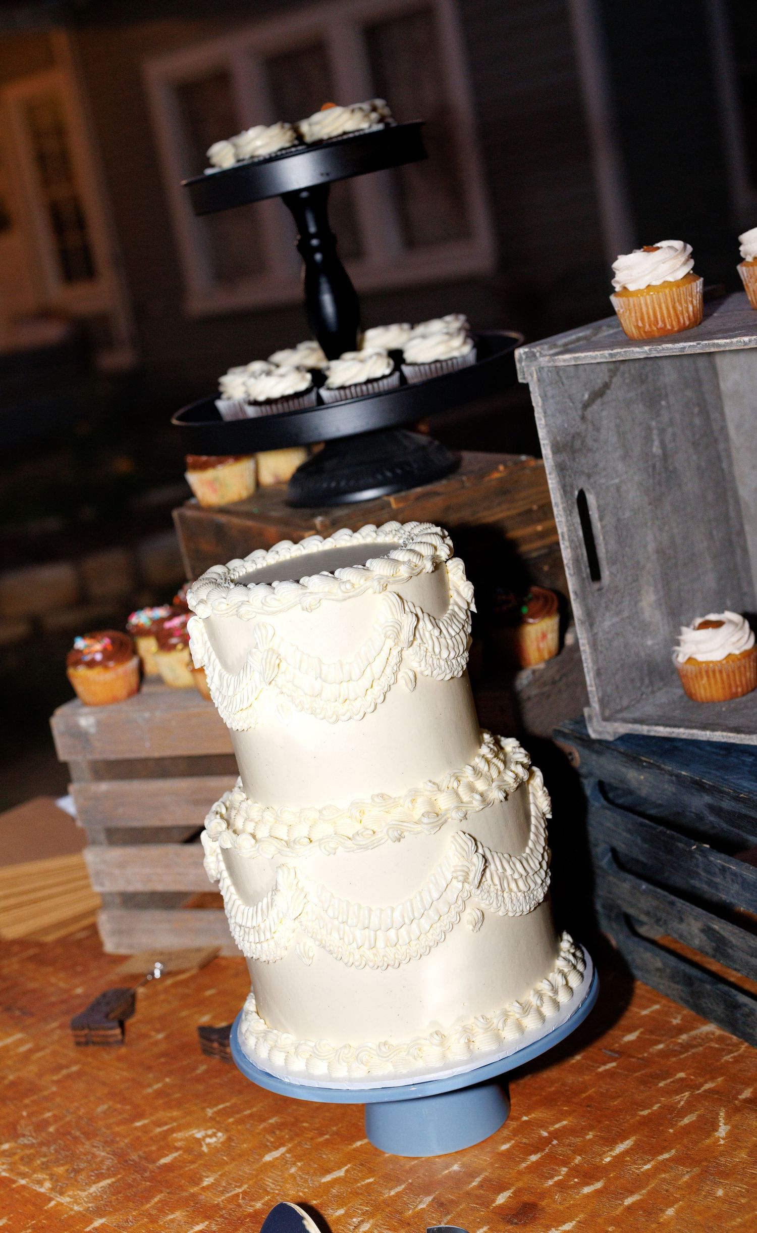 A sequence of images showing a white frosted wedding cake with cupcakes on a dark wooden table.