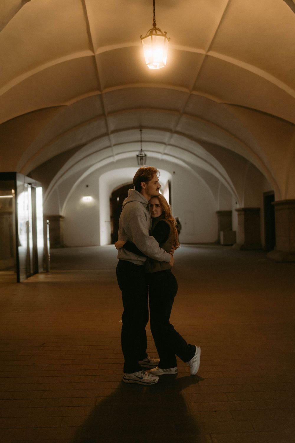 Dimly lit arched underground space with vaulted ceilings and dramatic shadows.