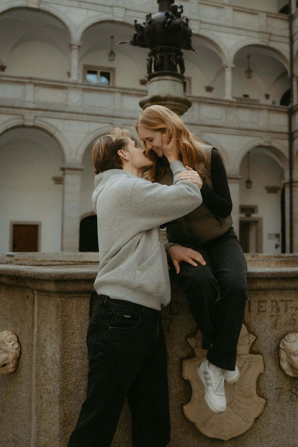 A romantic sequence of two people embracing and sharing tender moments against a stone wall with arches.