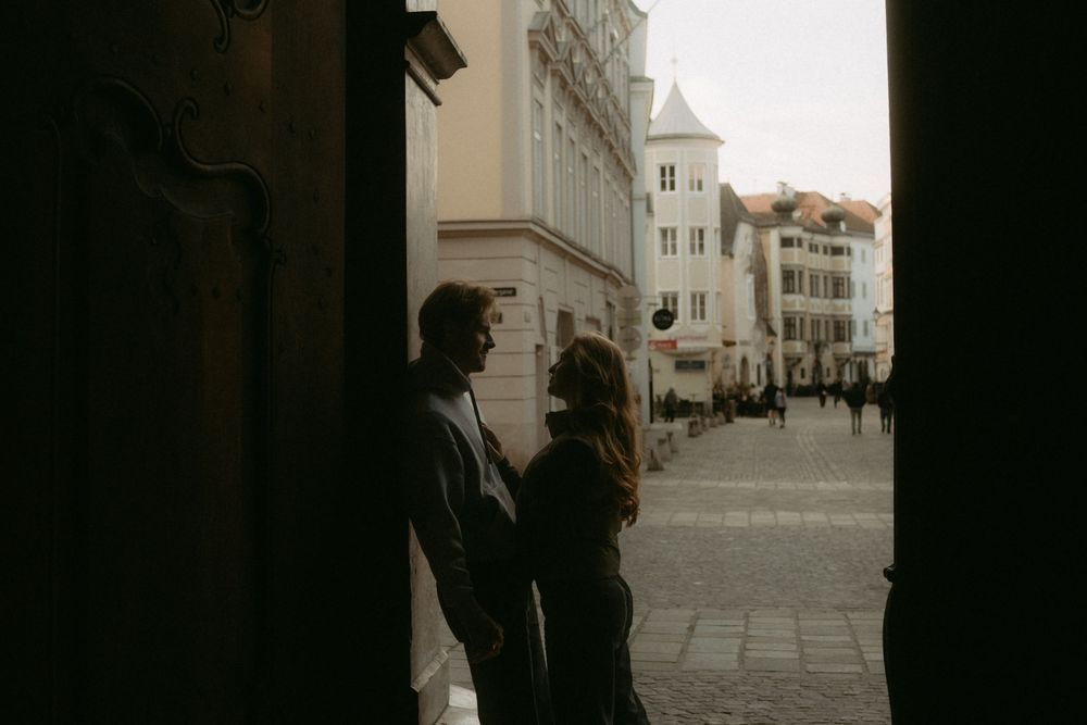 A series of black and white street photographs showing silhouettes of people walking along historic building facades.