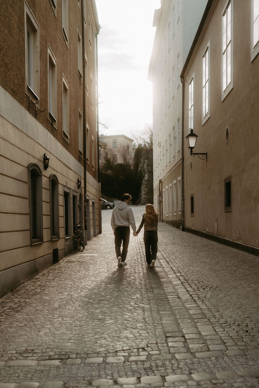 A sequence of sepia-toned images showing two figures walking down a narrow cobblestone street between tall buildings.