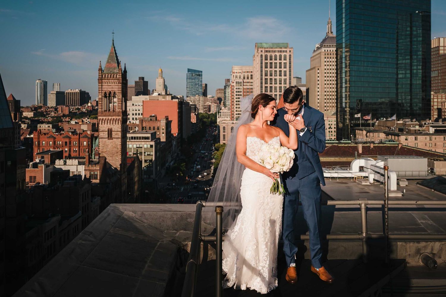 Bride and groom on Lenox Hotel Boston rooftop with city skyline views during golden hour wedding portrait