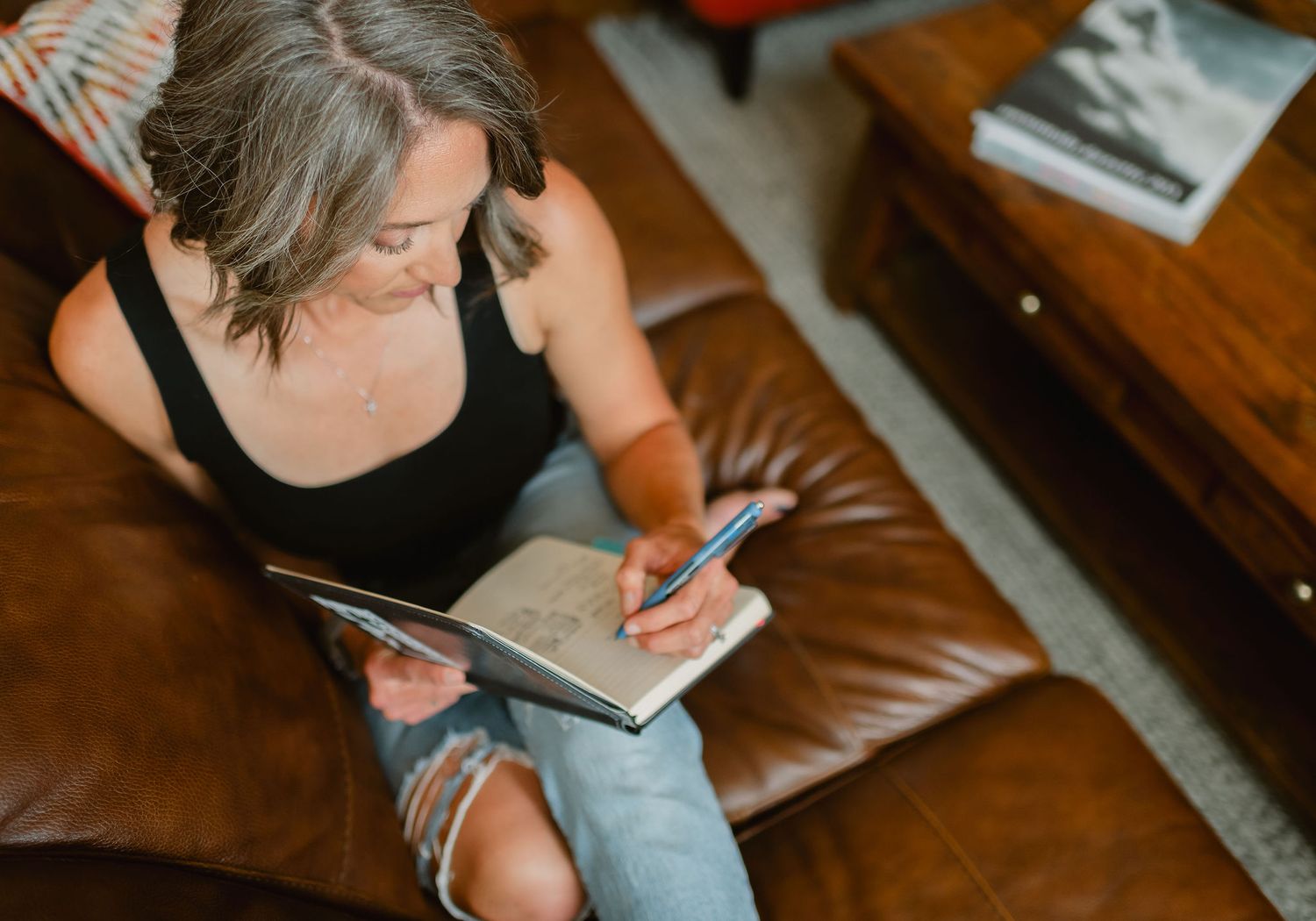 Colorado branding photographer writes in a notebook while sitting on in a cozy space