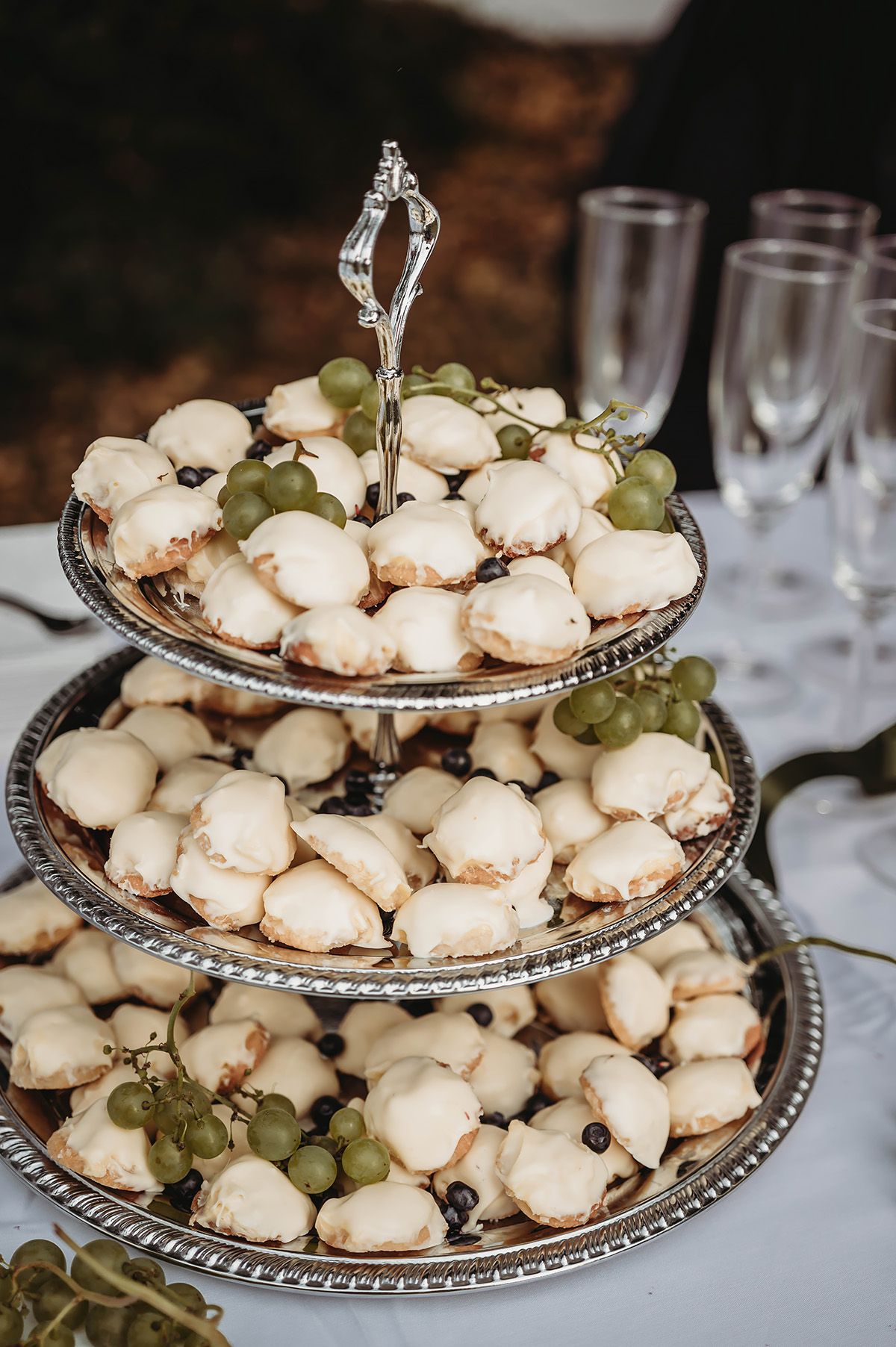 Dessert på bröllop vid brudskål i Norrköping, små biskvier uppdukade på ett silver kakfat i våningar. Bröllopsfotograf Josefin Landhagen.
