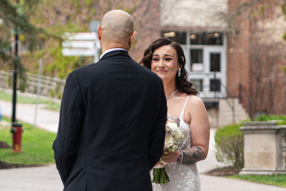 Bride smiles warmly at groom during outdoor first look wedding portrait session.