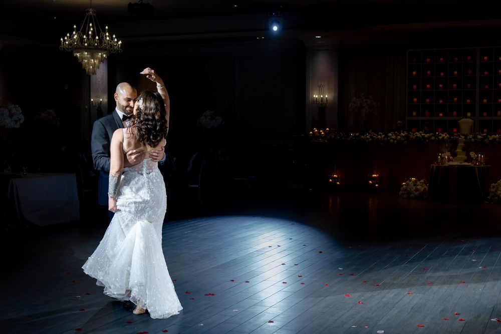 Bride and groom share a romantic first dance in a softly lit wedding ballroom.