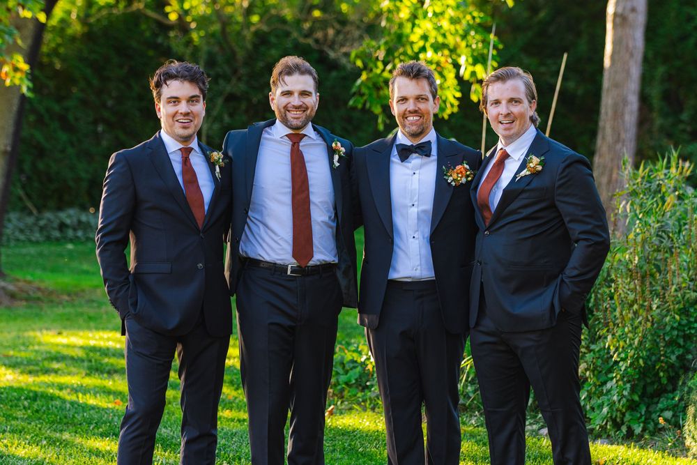 Four men in suits standing together in a garden.