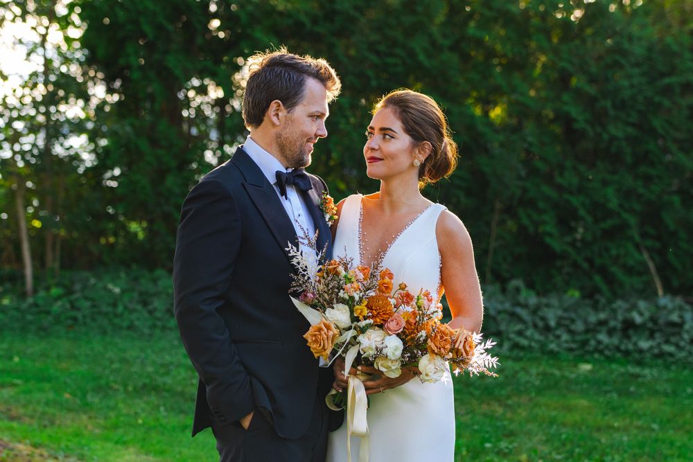 A bride and groom embracing in a garden setting.
