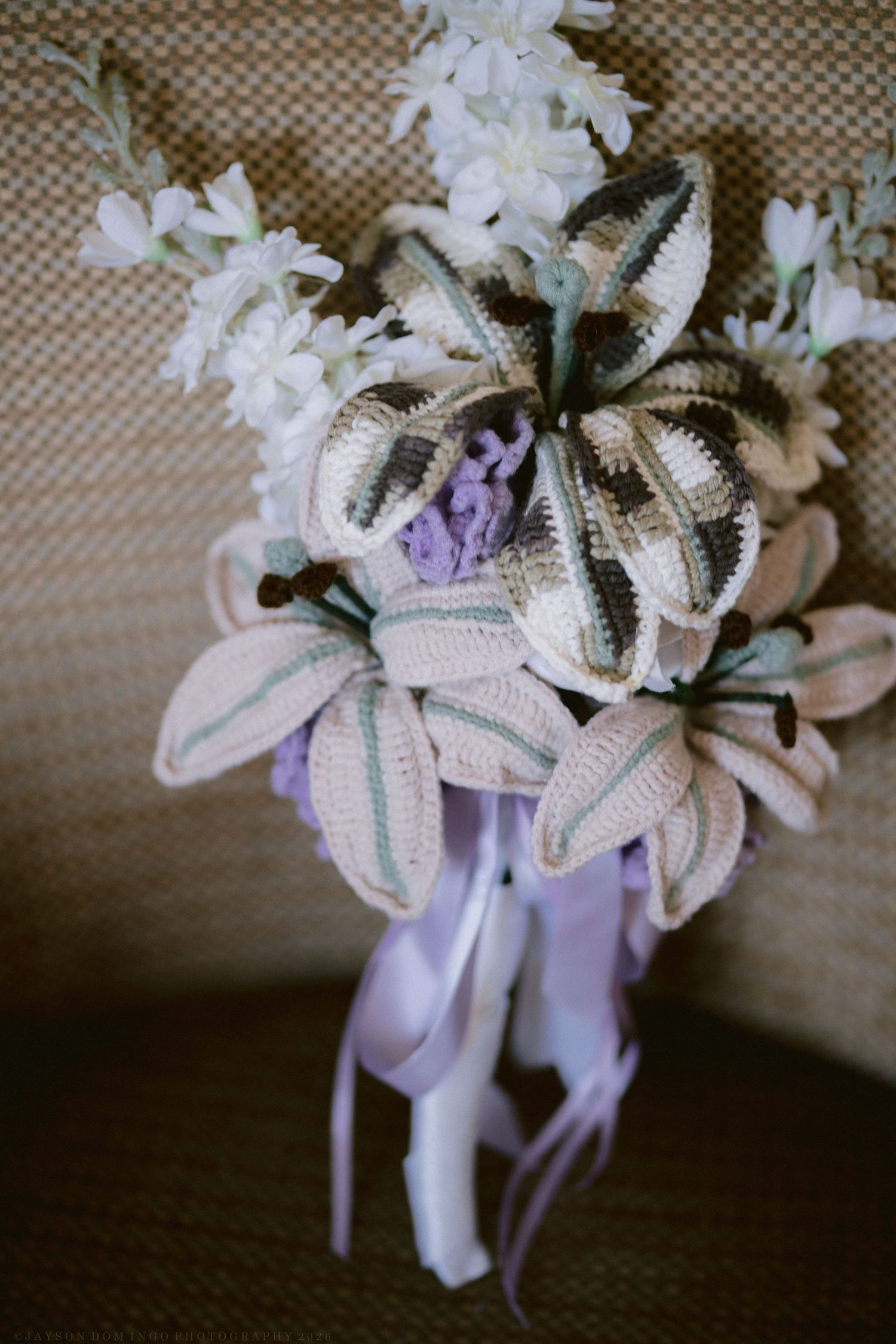 Handmade crochet wedding bouquet with cream and green striped flowers, purple accents, and lavender satin ribbons.