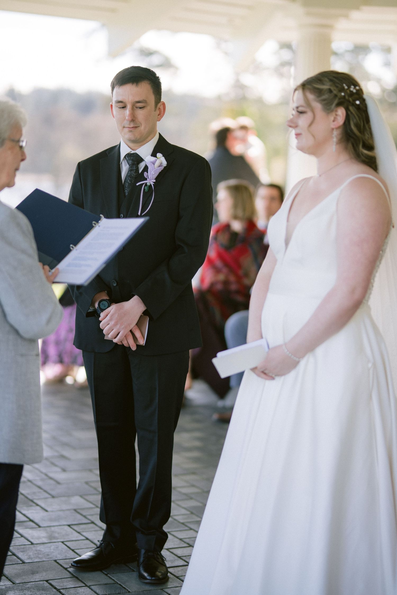 Bride and groom exchanging vows during outdoor wedding ceremony with officiant.