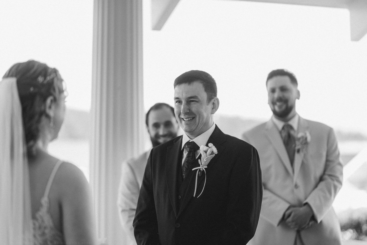 Groom smiling joyfully at bride during outdoor wedding ceremony.