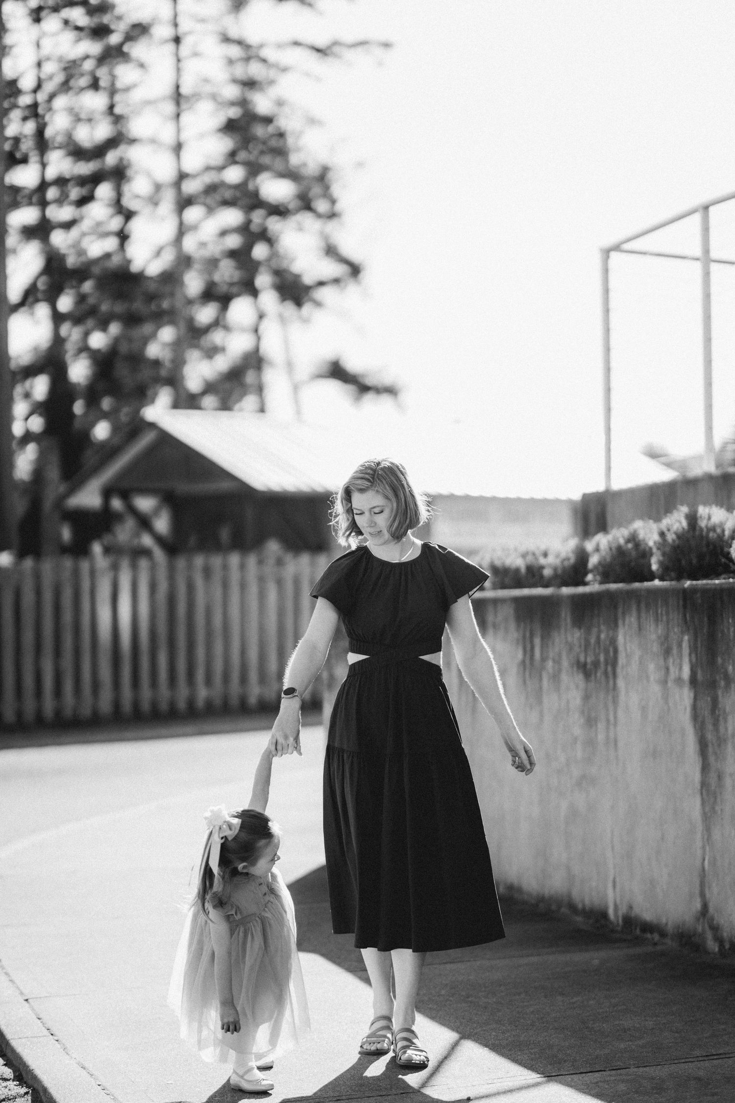 Black and white photo of mother walking with young daughter outdoors.