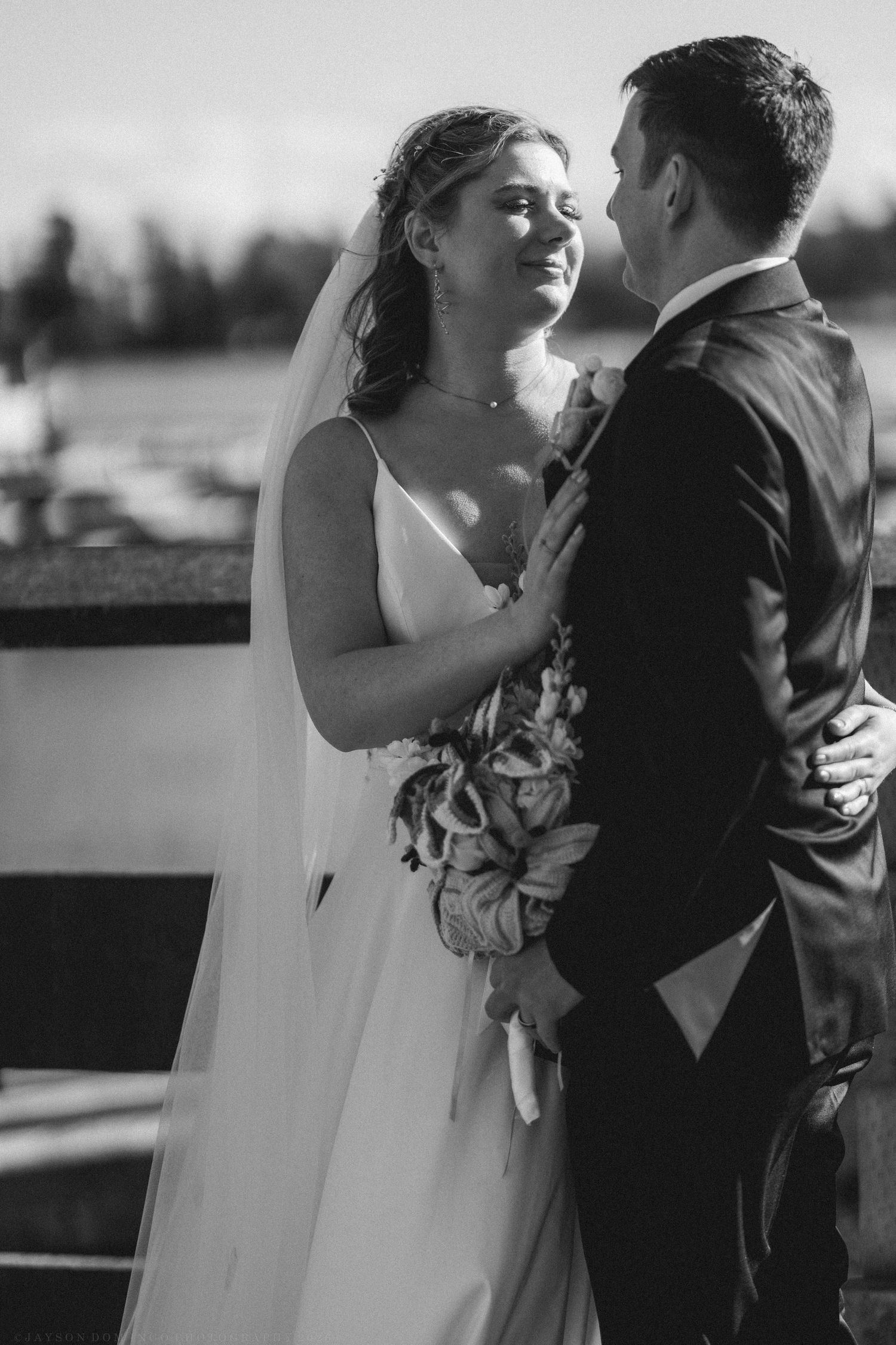 Black and white photo of bride and groom sharing a romantic moment outdoors on their wedding day.