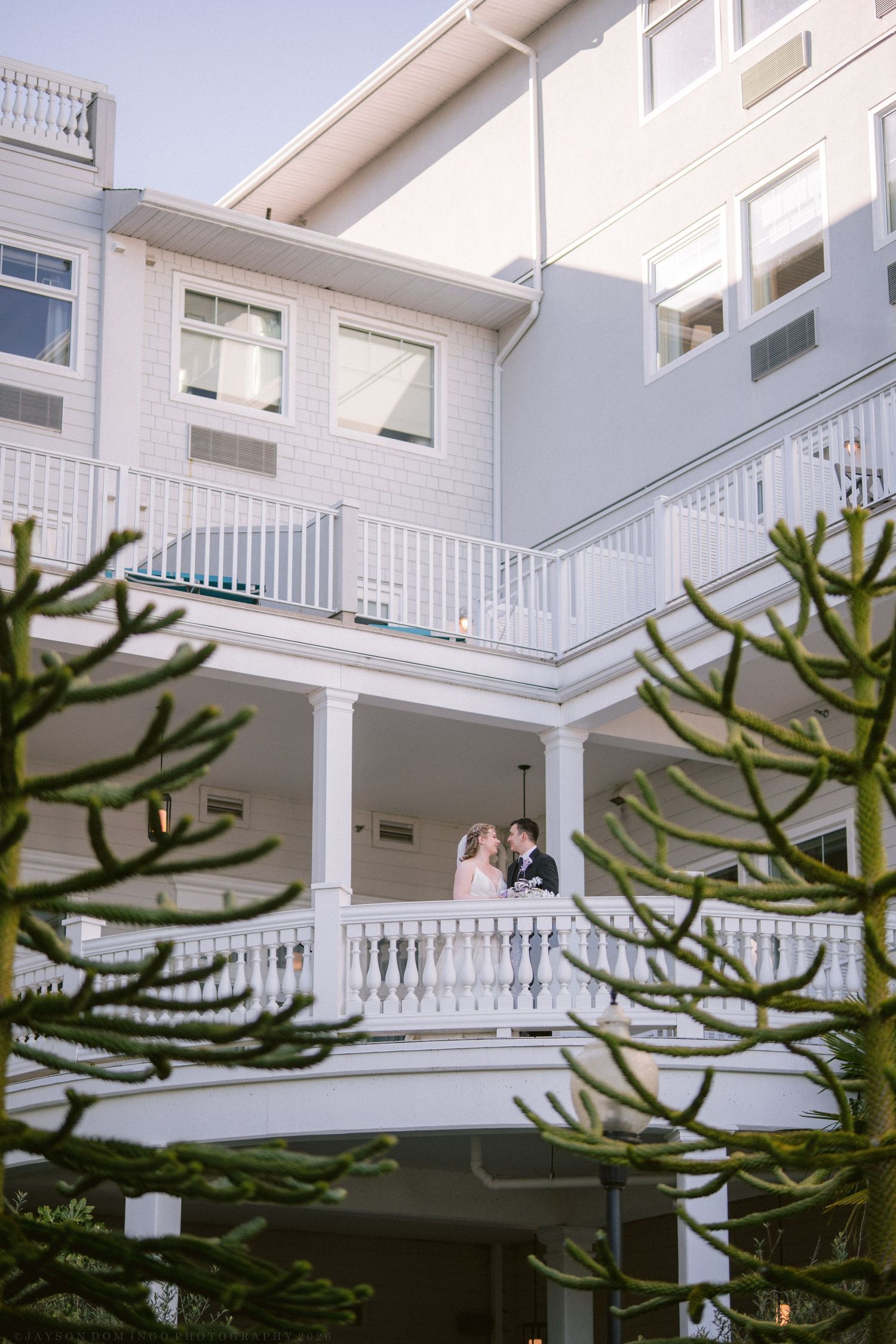 Wedding couple sharing romantic moment on hotel balcony at dusk.
