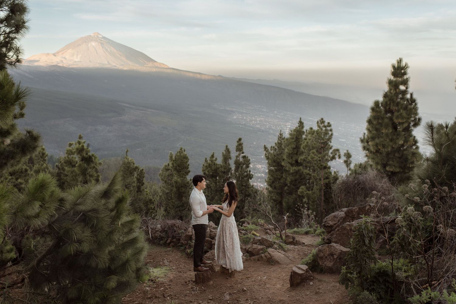 A couple poses for wedding photos with Mount Hood visible in the distance during sunset.