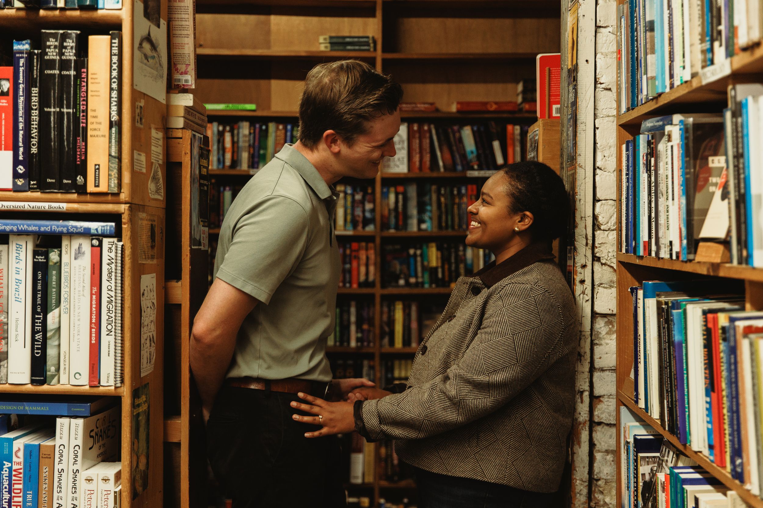 People browsing books in a cozy used bookstore with wooden shelves filled with various titles.