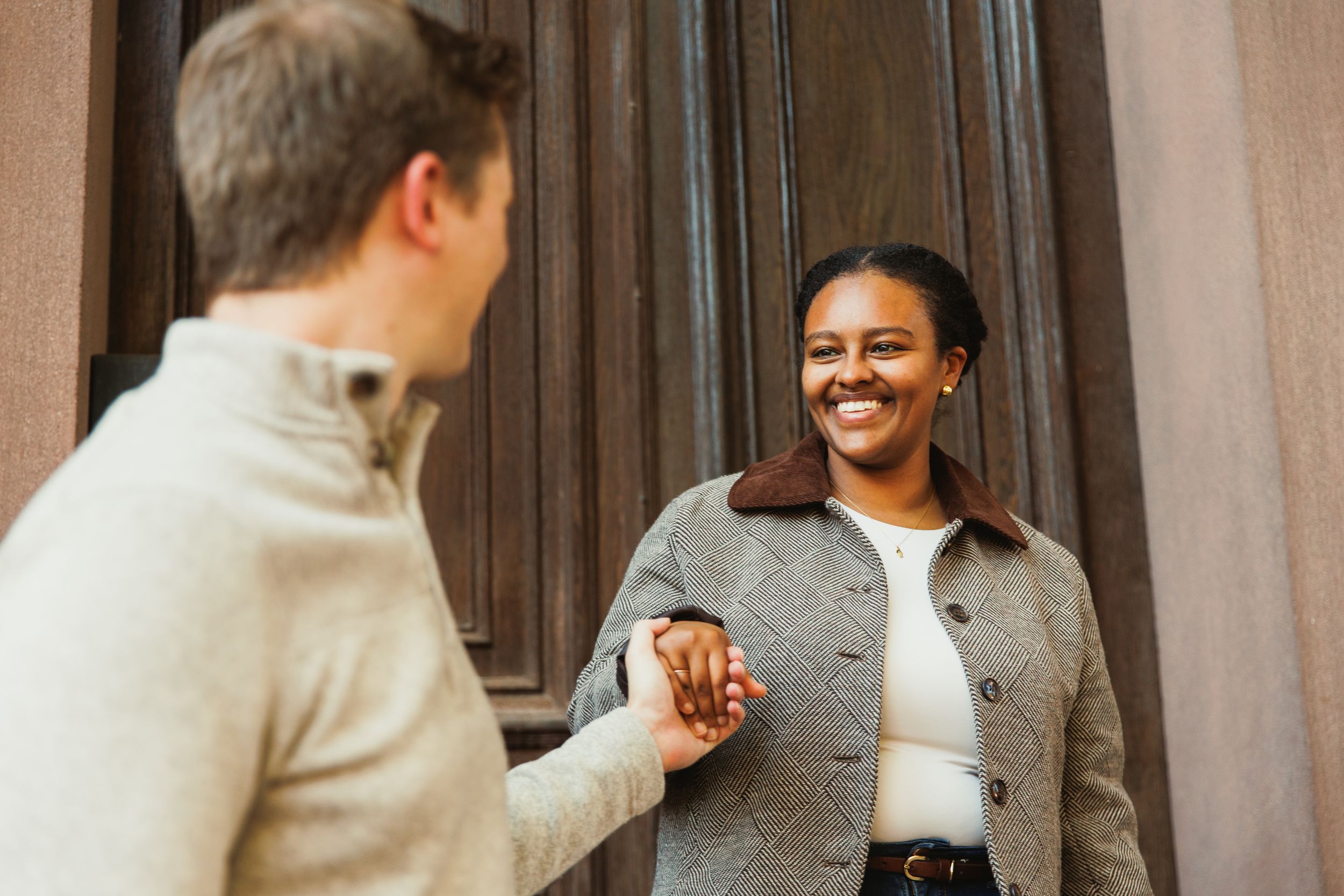 A couple sharing a joyful moment while standing by a wooden door.