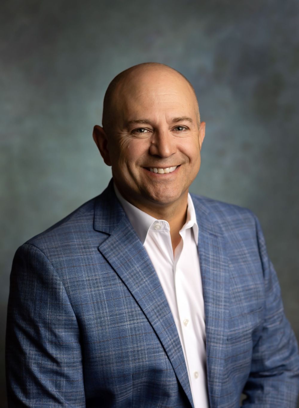 Professional headshot portraits of someone in a blue plaid blazer and white shirt against a gray backdrop.