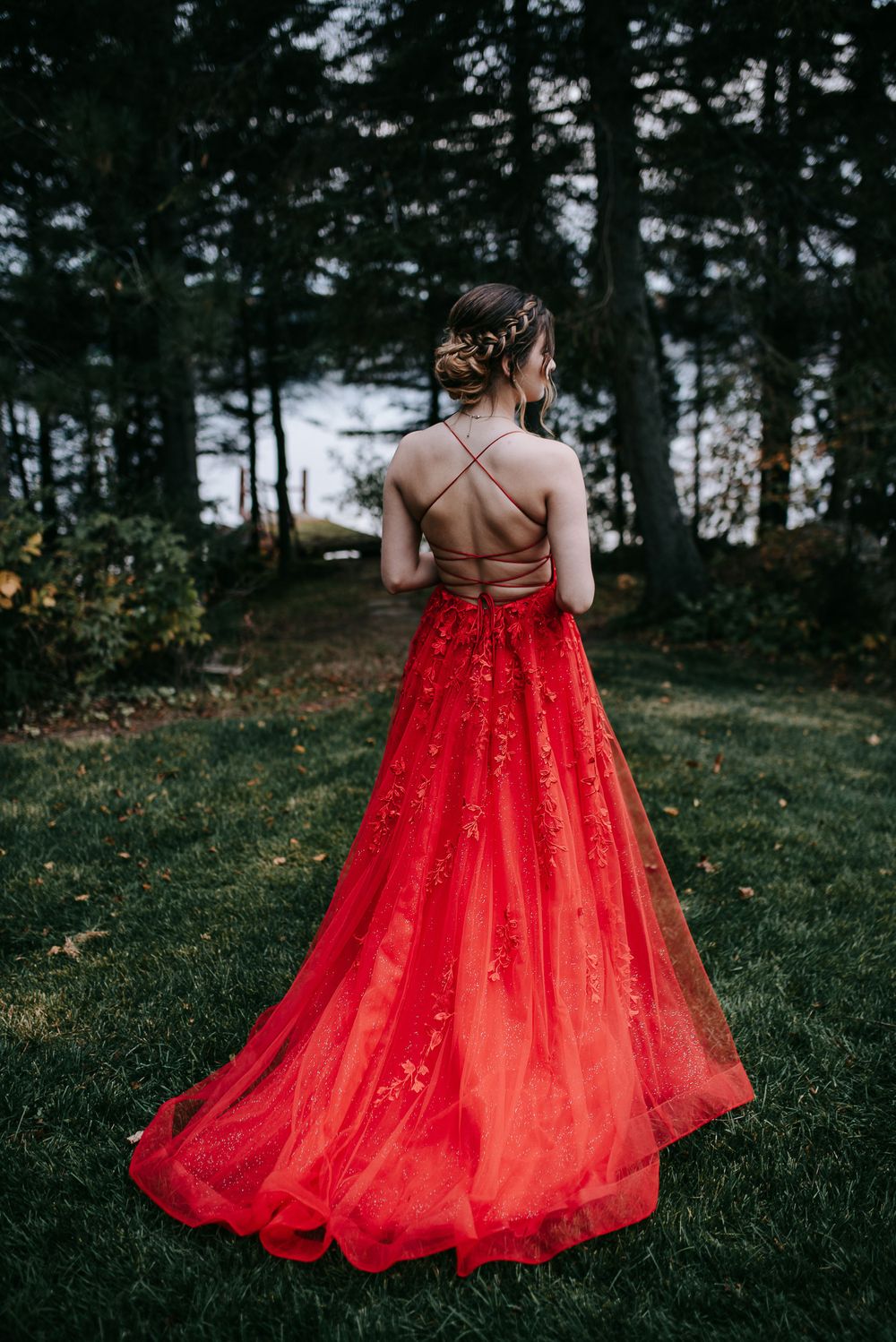 Flowing red sparkly ballgown twirls gracefully against dark forest backdrop.