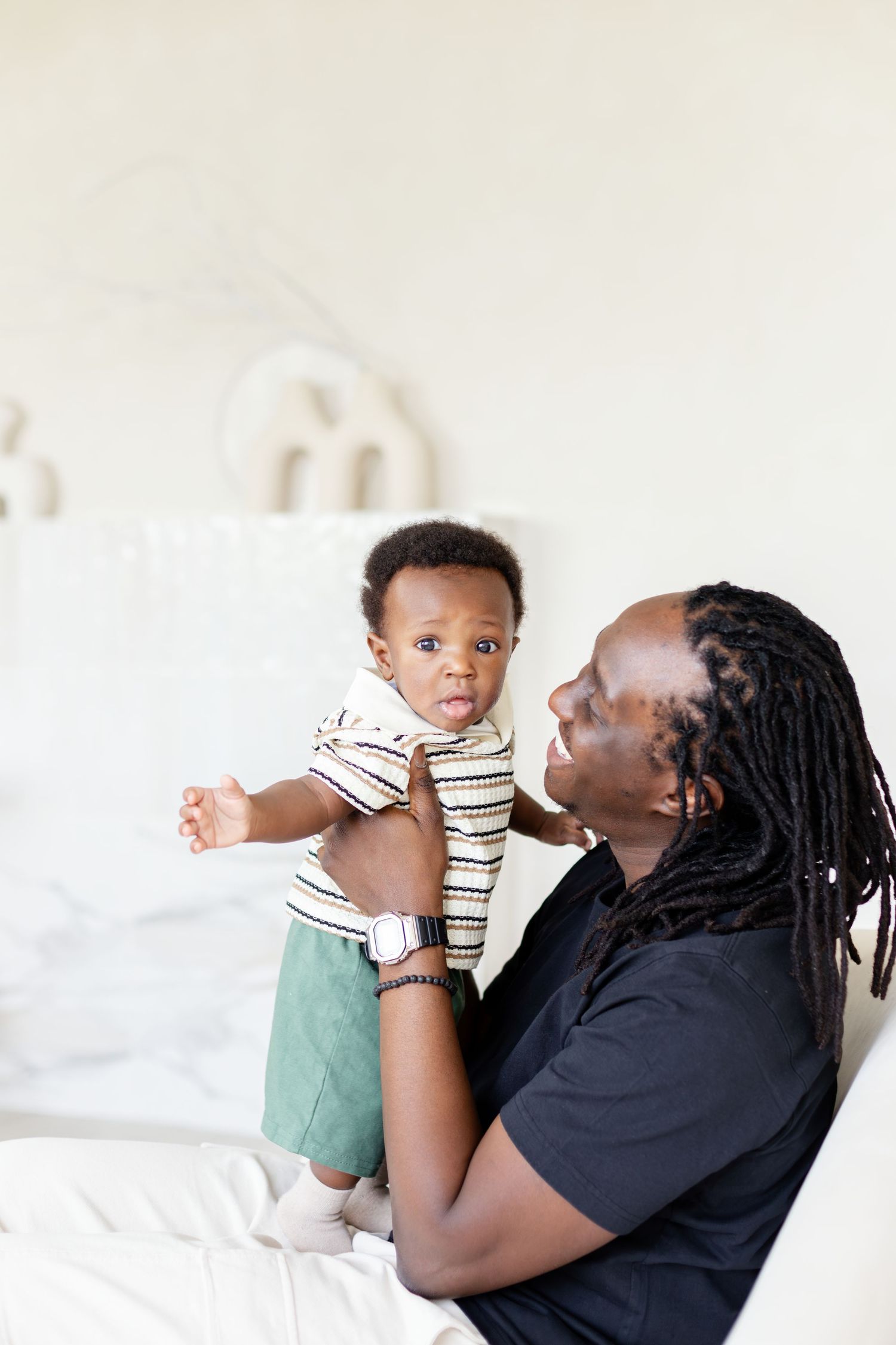 A parent and baby share playful moments together on a white bed in a sequence of three connected photos.