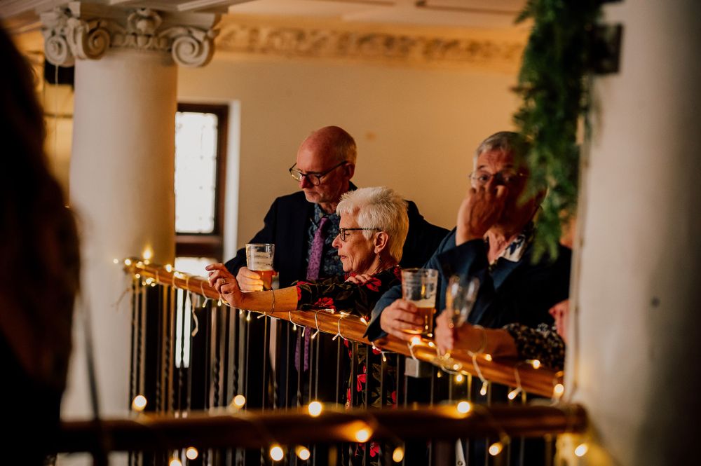 People gathered at an elegant bar with ornate columns and golden decorative lighting during an evening event.