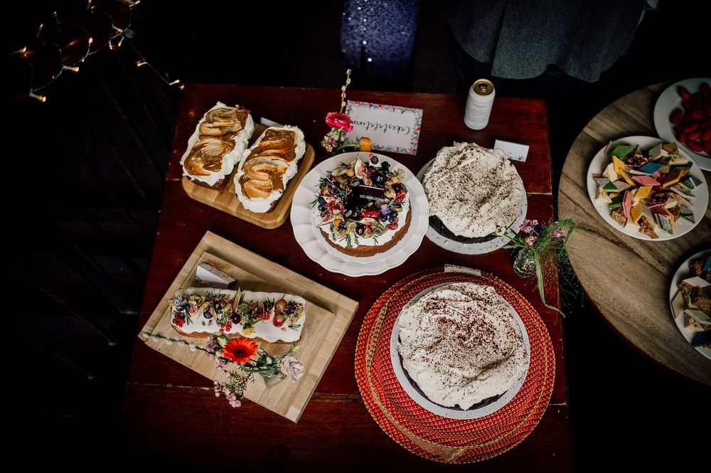 Overhead view of a festive dinner table with various desserts, pastries, and decorated plates on a dark wooden surface.