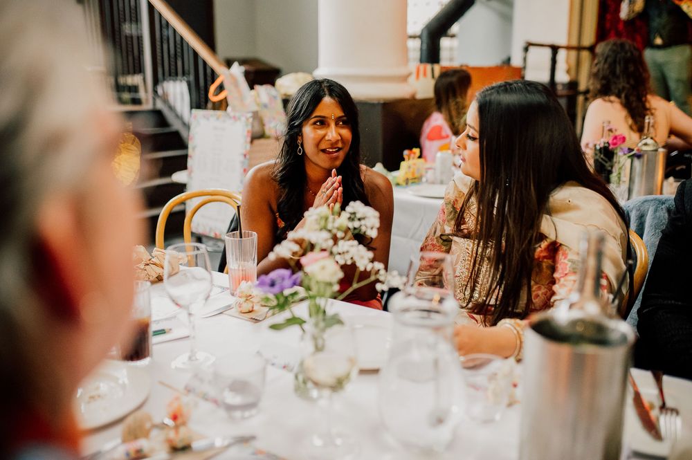 Guests engage in lively conversation at an elegant dinner party with floral centerpieces and candlelight.