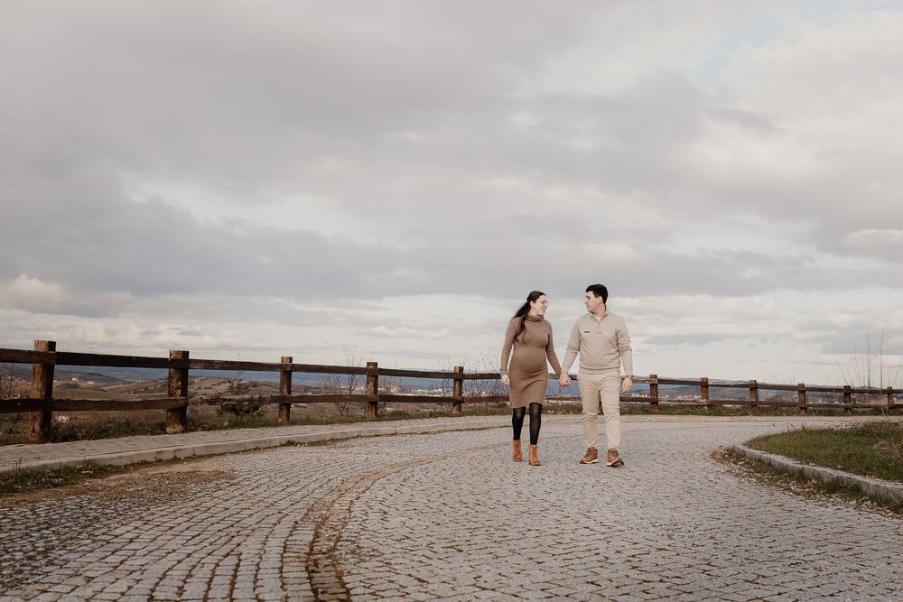 A couple walks along a winding wooden boardwalk path near the beach on a cloudy day.