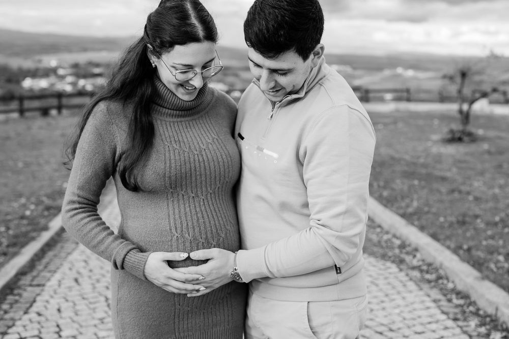 A couple sits together outdoors sharing tender moments in black and white photography.