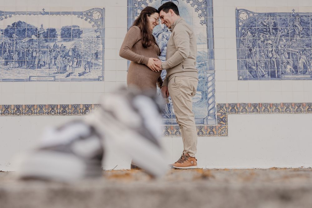 A couple embraces against a wall decorated with blue and white Portuguese azulejo tiles.