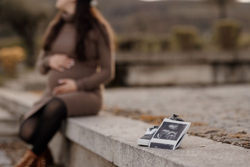 A vintage Polaroid camera sits on a concrete ledge while someone sits blurred in the background.