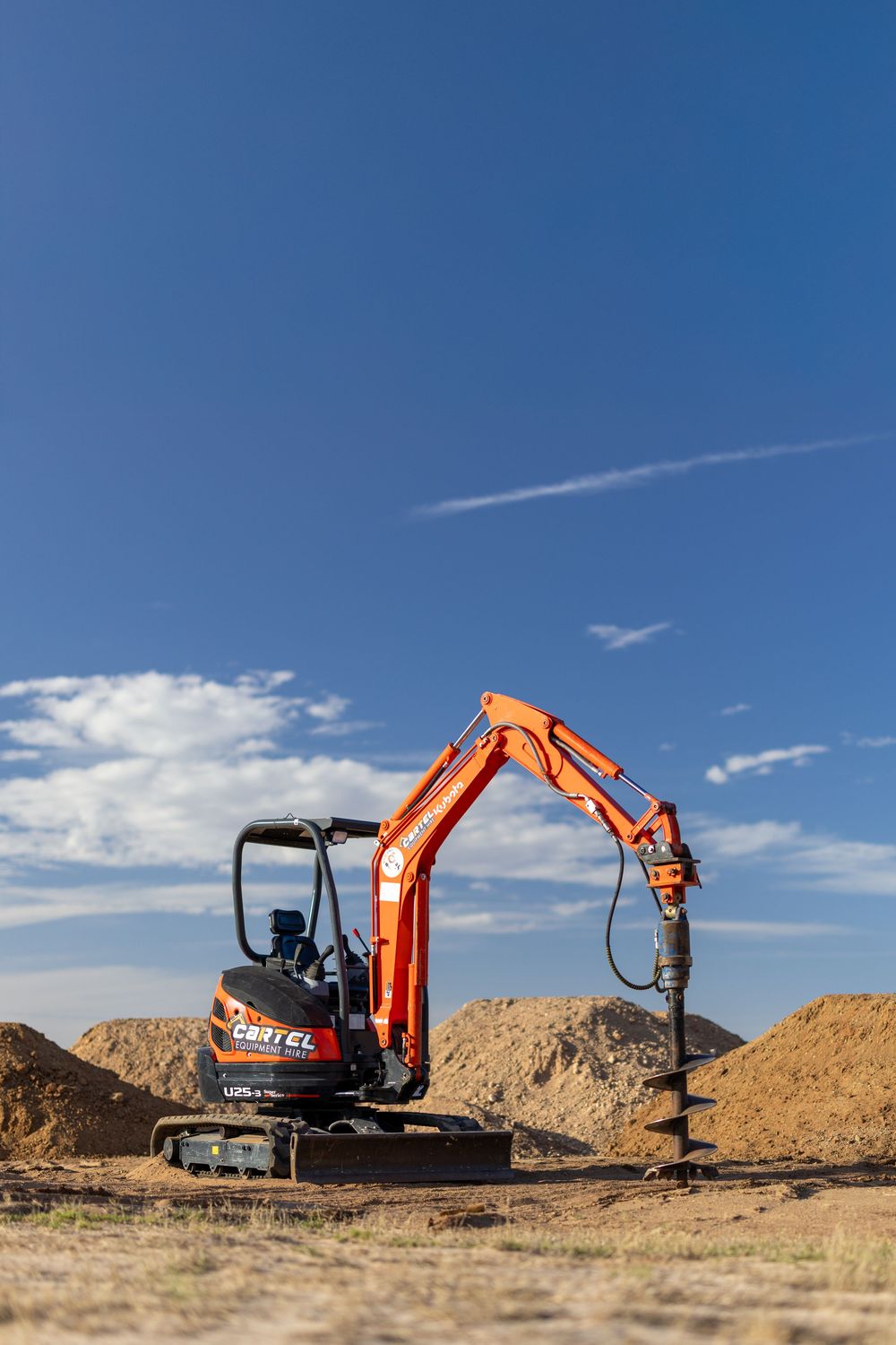 Mini excavator with auger drilling holes on dirt site