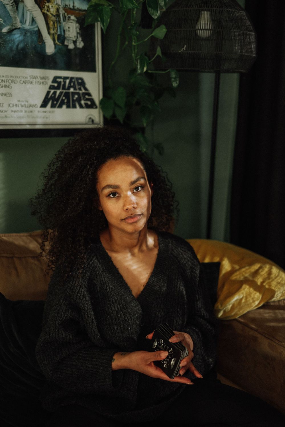 A moody portrait featuring curly hair and dramatic lighting against a dark background.