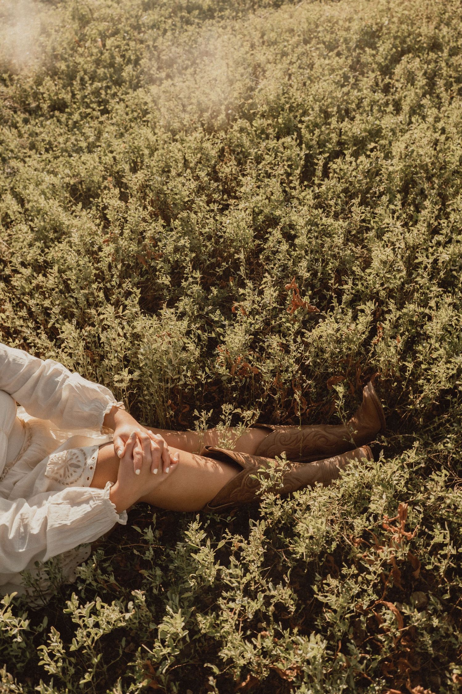 Legs resting in a dreamy field of wild herbs and flowers on a sunny afternoon.