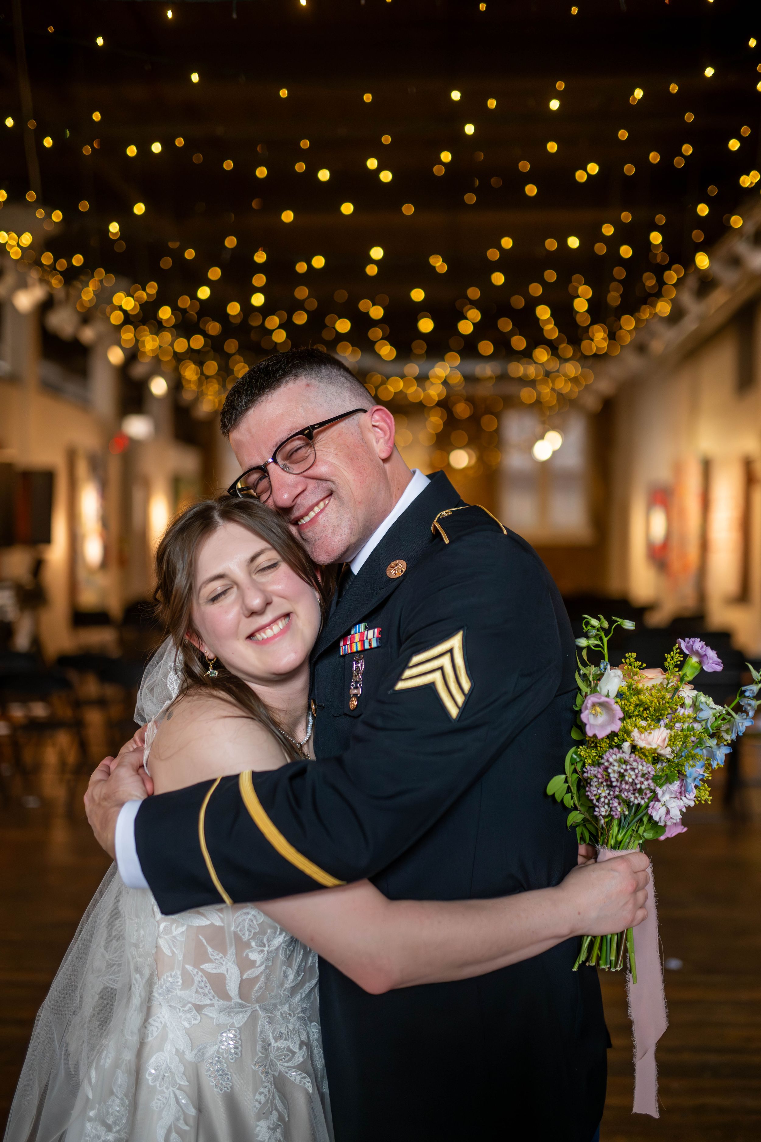 A romantic moment between a couple in wedding attire dancing under twinkling lights.