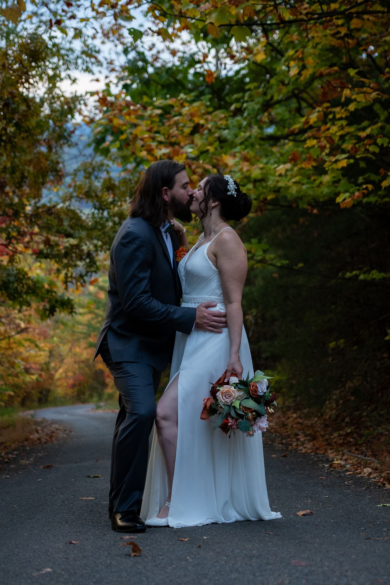 A romantic moment between a couple in formal attire beneath a stone tunnel.