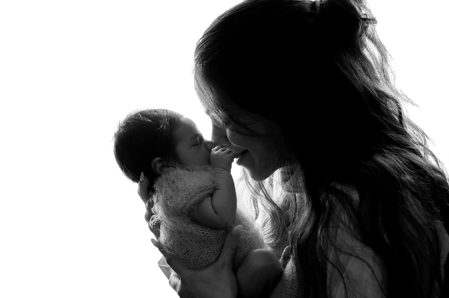 Silhouette of tender moment between mother and newborn baby in black and white.