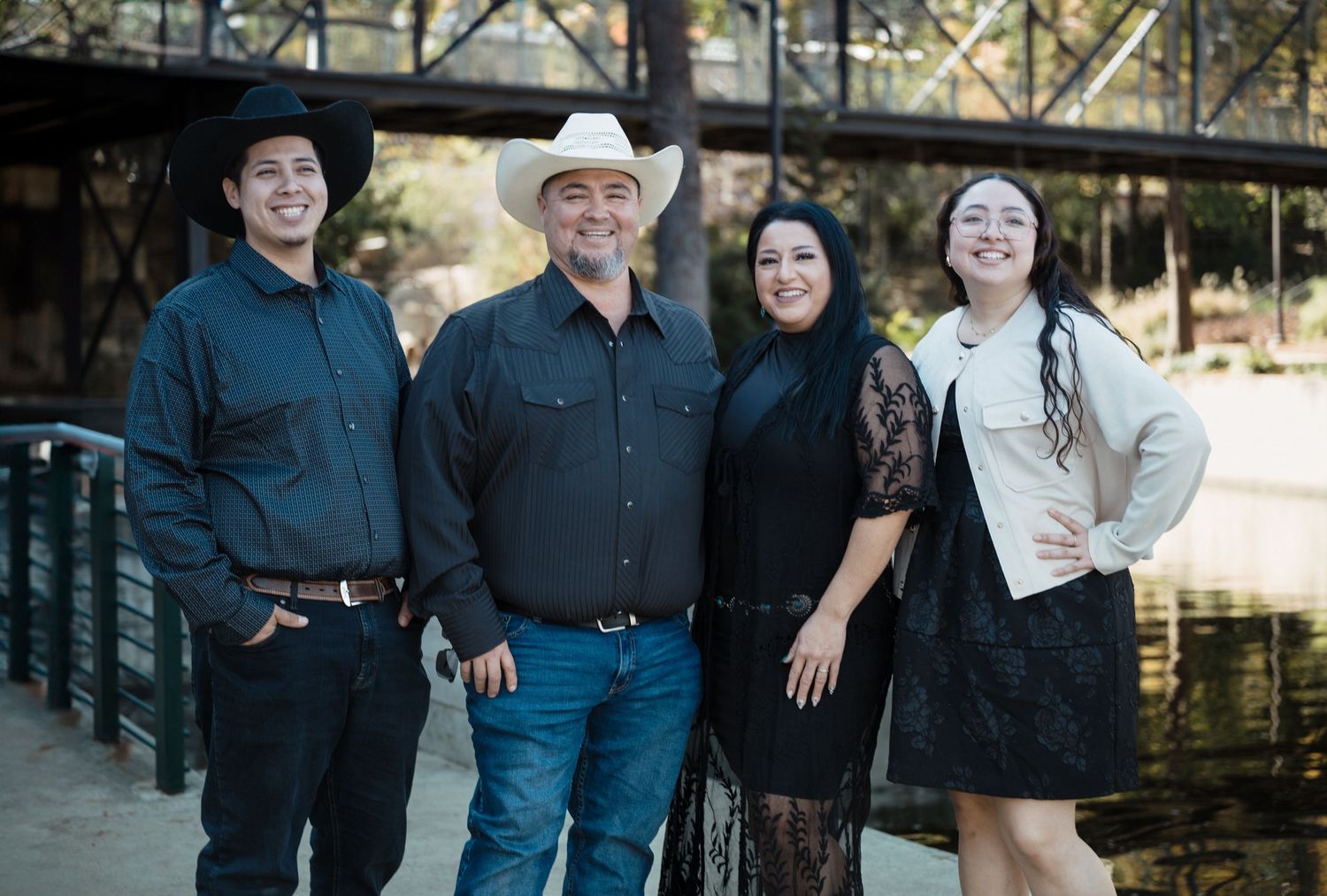 Family portrait of four people on a wooden bridge with water in the background.