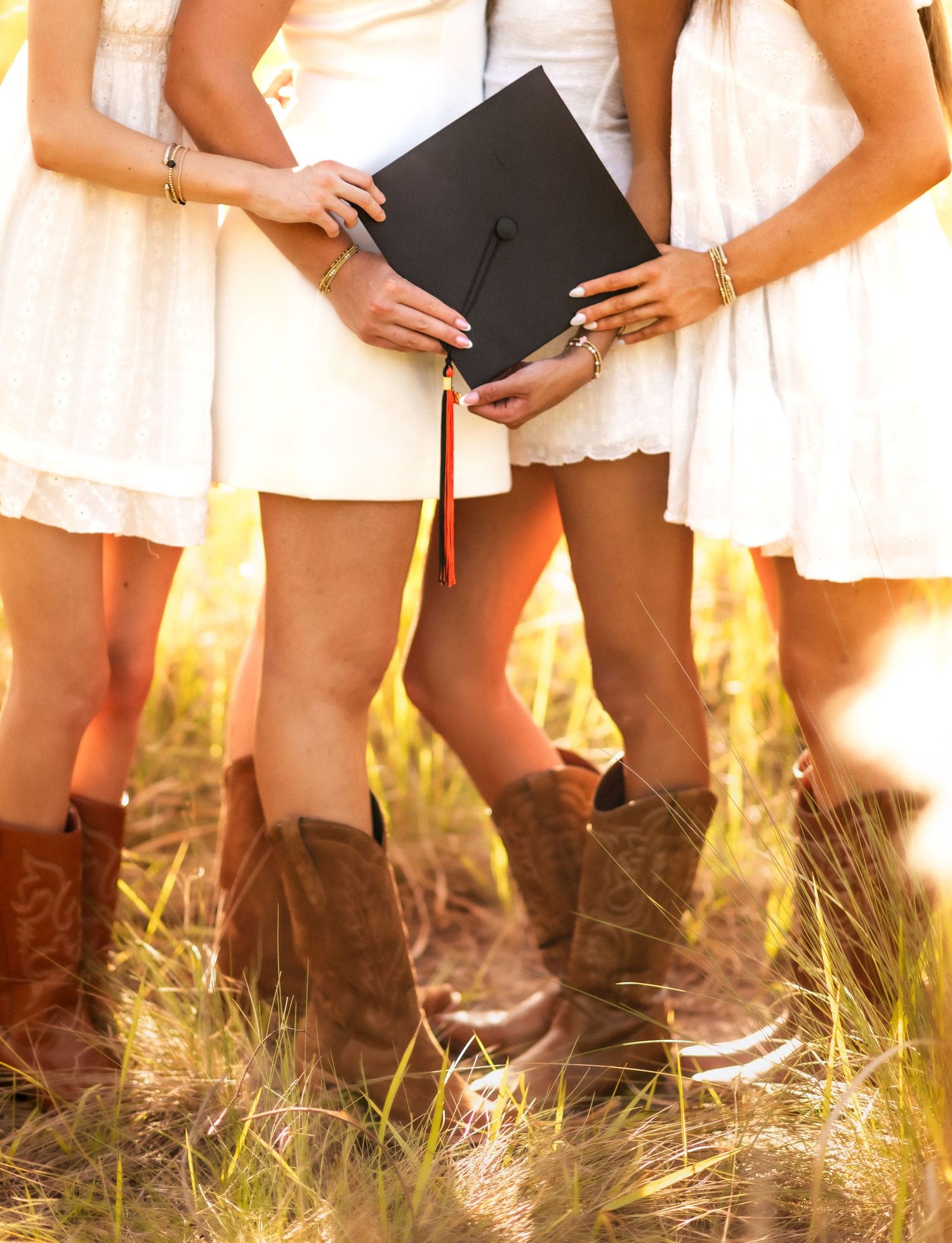 Smiling blonde teen in red Blazers State crop top and white jeans posing in a golden grass field.