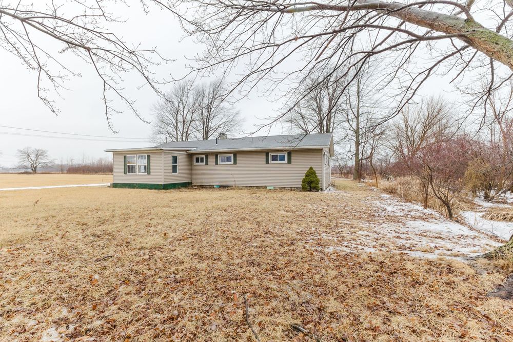 Single-story ranch home surrounded by bare winter trees and frost-covered grass on a spacious lot.