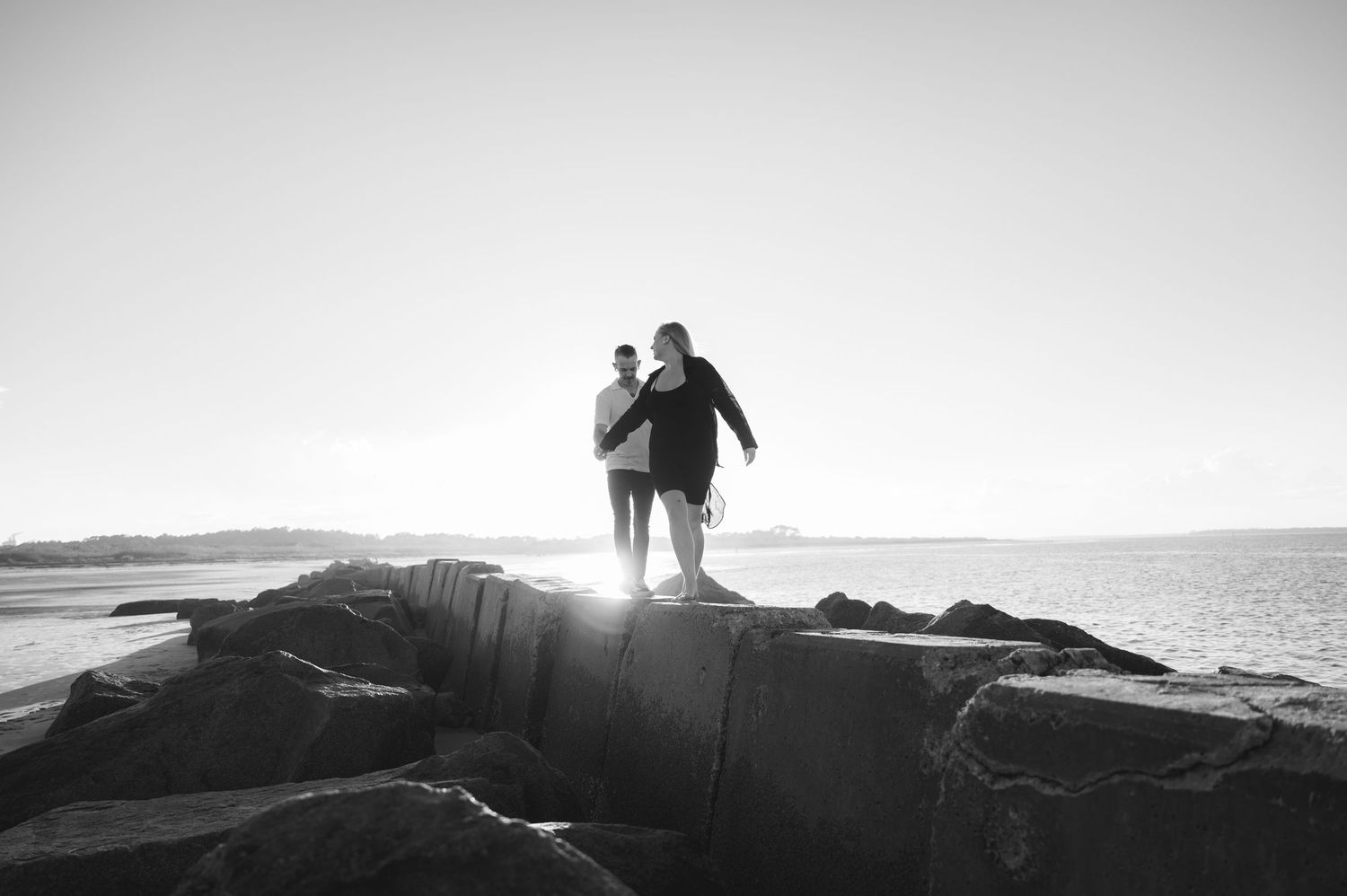 A silhouetted couple walks along a misty mountain ridge at sunset, creating a dramatic backlit scene against the sky.