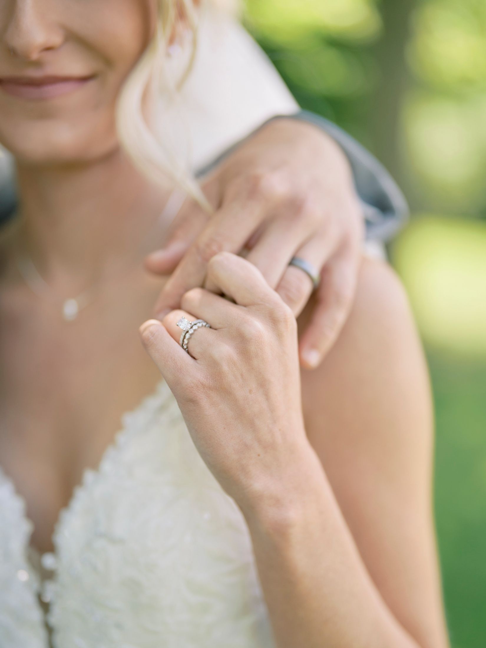 Close-up of bride and groom hands showing diamond engagement ring and wedding bands after ceremony.