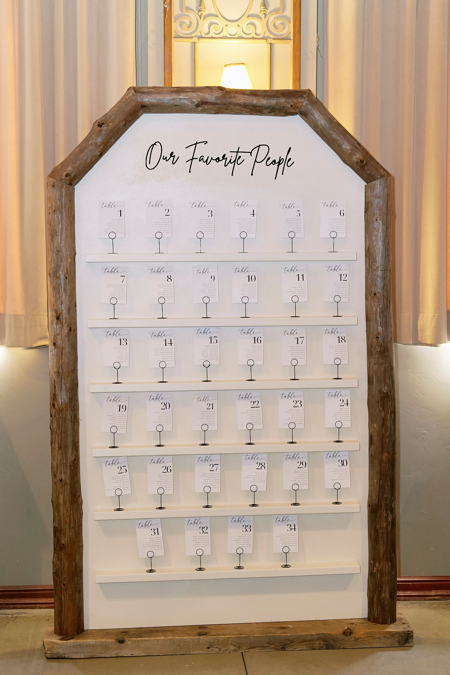 Rustic wooden wedding seating chart sign titled Our Favorite People with table assignments.