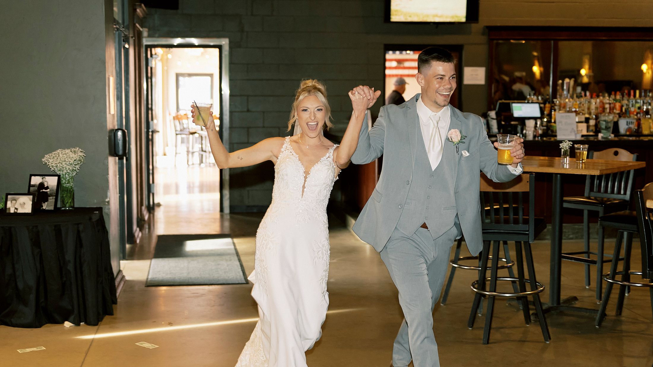 Bride and groom making grand entrance at wedding reception venue holding hands and smiling.