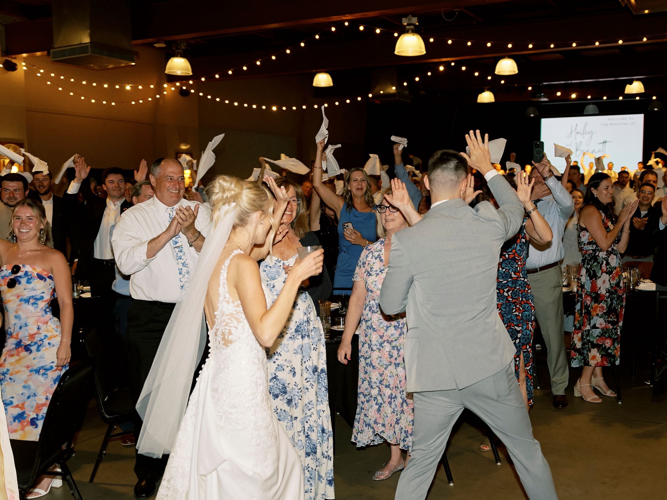 Bride and groom celebrating with guests on a lively wedding reception dance floor.