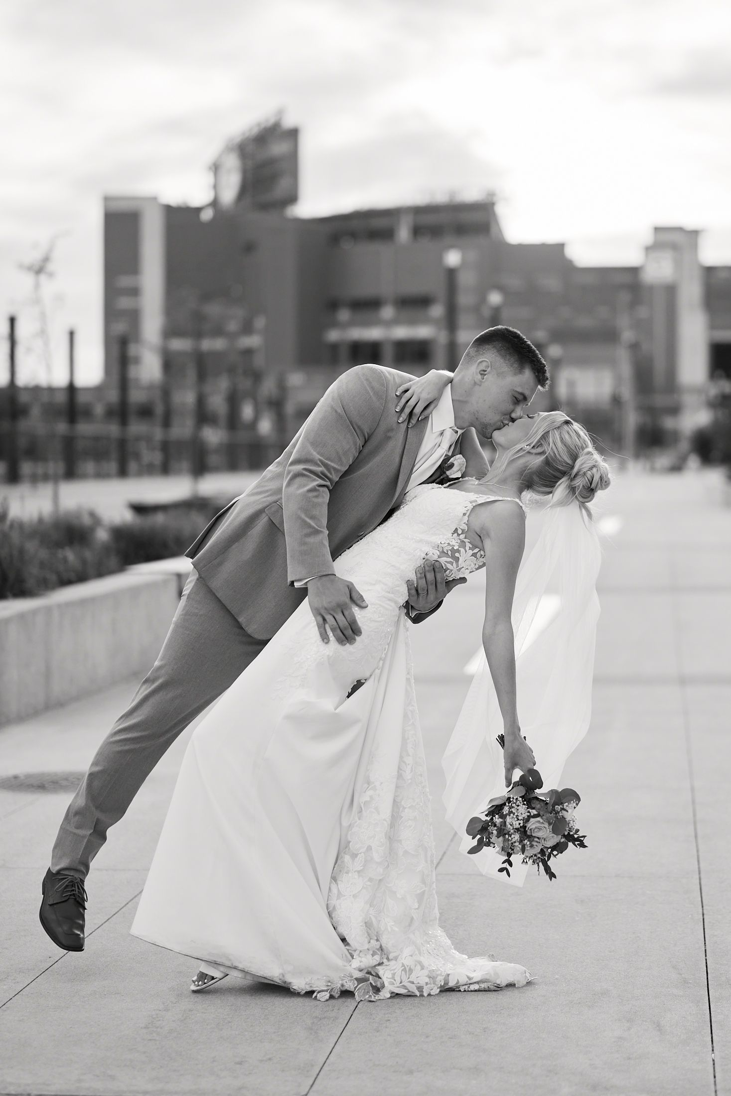 Black and white photo of groom dipping bride for a kiss outdoors on their wedding day.