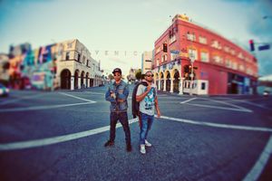 Two men stand together in the middle of a Venice Beach street intersection using a fisheye lens effect.