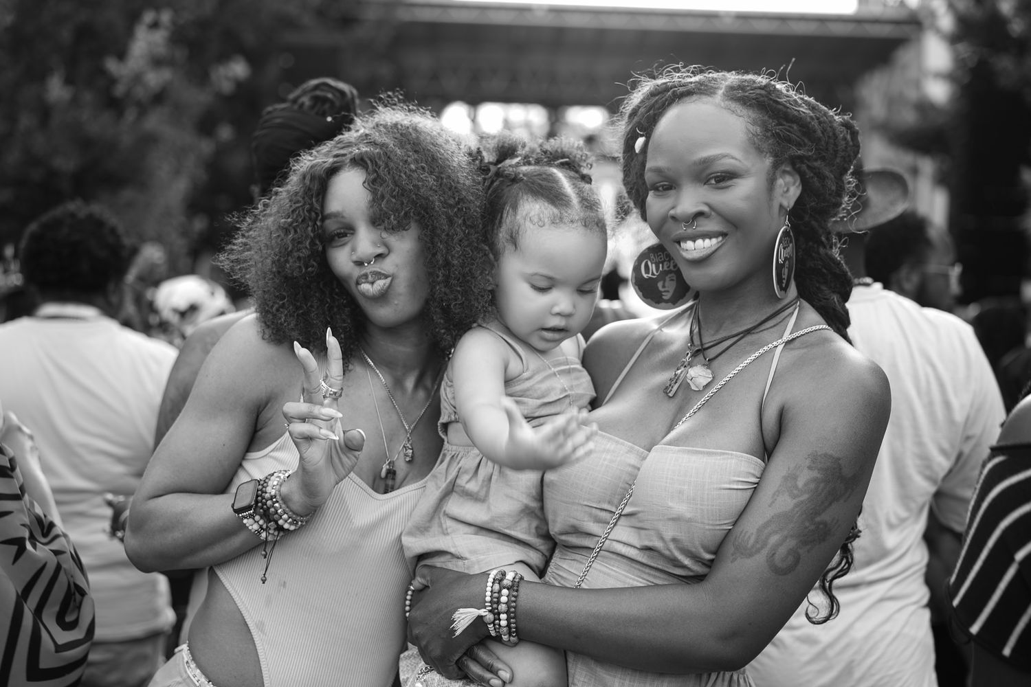 Young Black couple holding hands on a sunny street, woman in tube top and denim shorts, man in white tee and gray shorts.